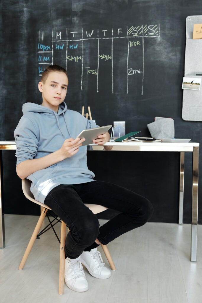 boy-in-gray-hoodie-and-black-pants-while-sitting-on-chair-4144692